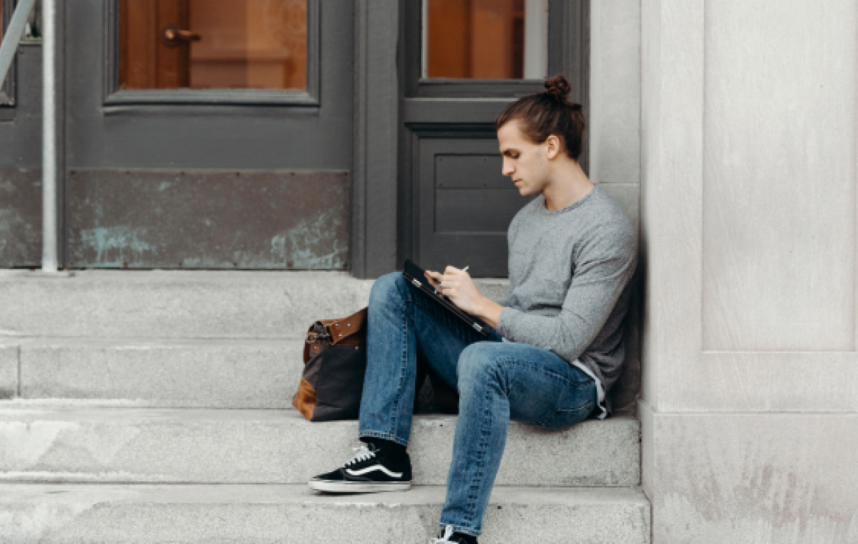 Man sitting on staircase, reading phone.
